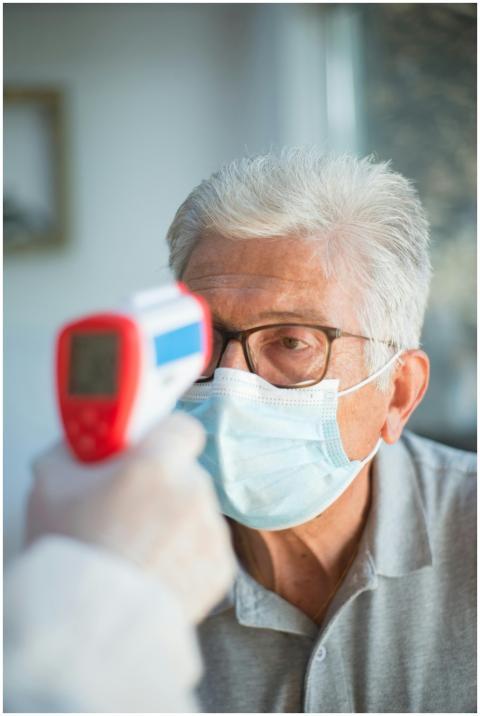 A senior man with white hair and eyeglasses gets h