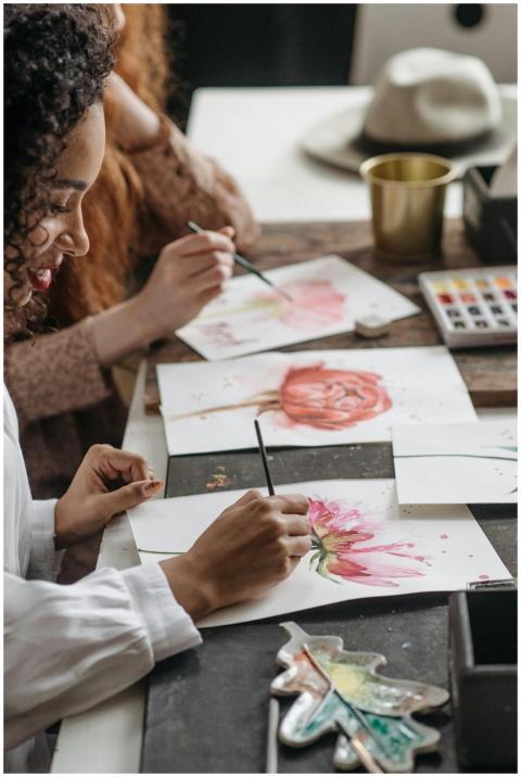 Focused women painting watercolor flowers at an in