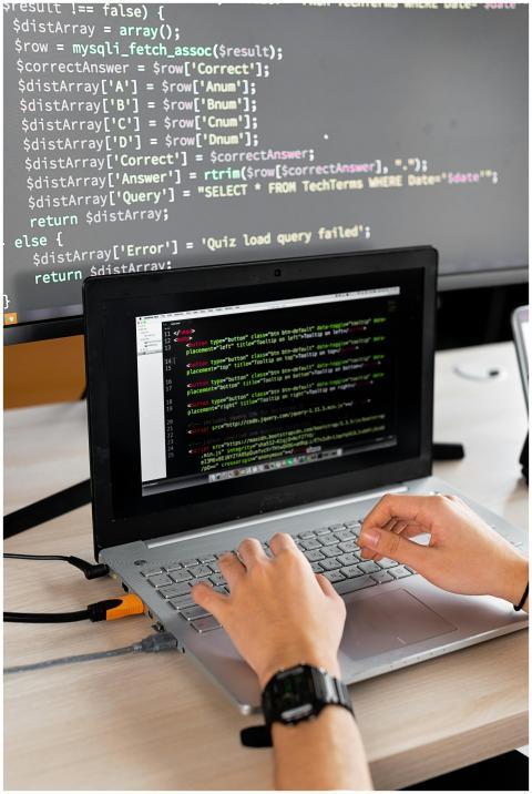 Person coding at a desk with laptop and external m