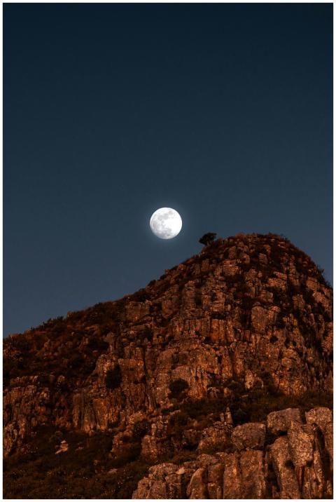 Full moon rises over a rocky cape in South Africa'