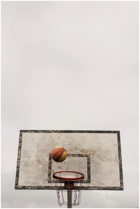 A basketball approaches the hoop against a cloudy
