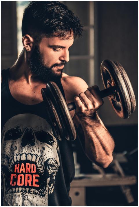 Bearded man in gym lifting a heavy dumbbell, showc