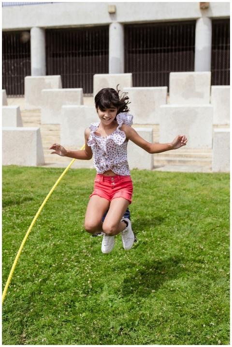 A young girl happily jumping rope on a grassy fiel