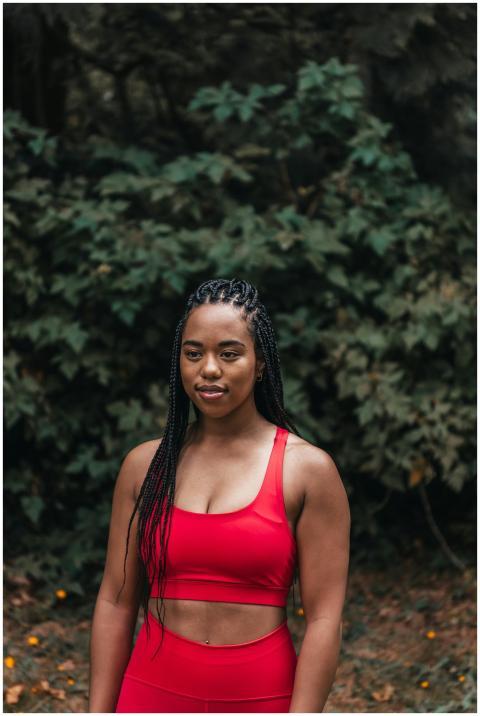 Young black woman in red activewear standing confi