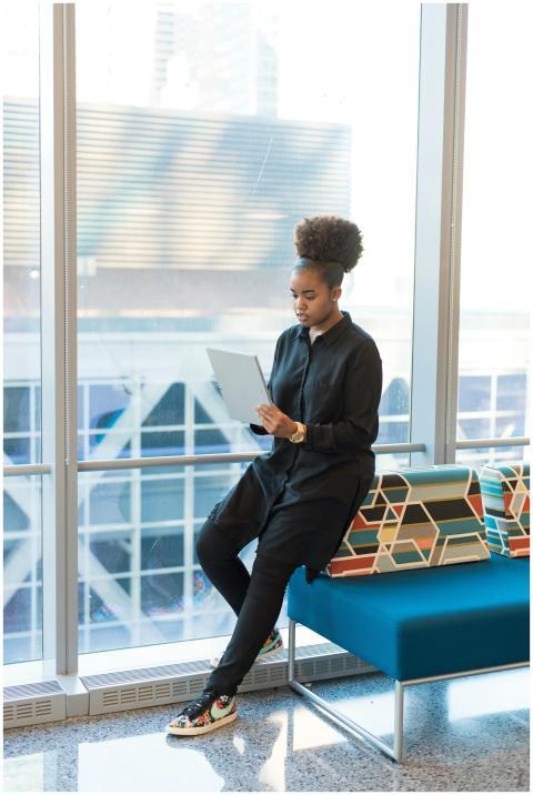 Woman sitting by window with tablet in a modern of