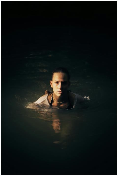 A serene portrait of a woman swimming in a dark la