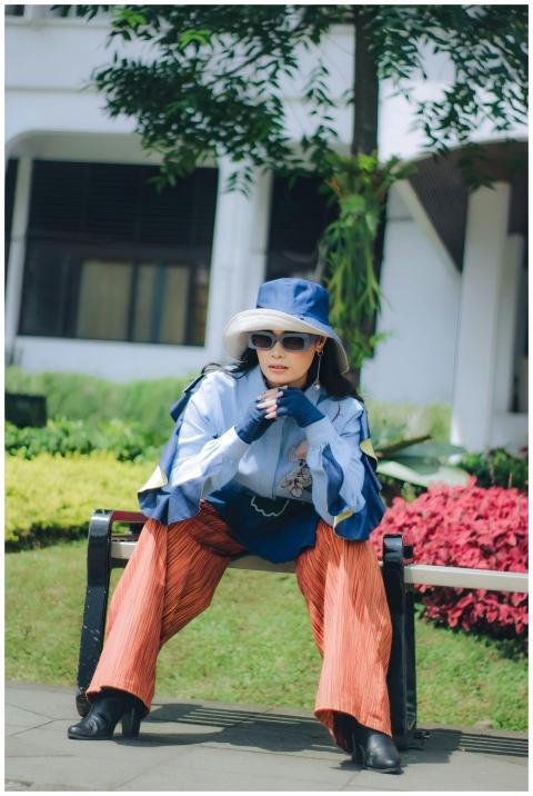 Stylish woman in a hat poses outdoors in a sunny B