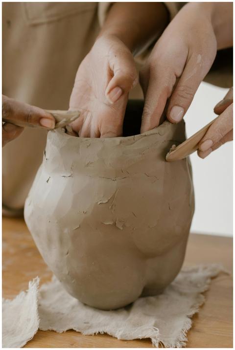 Detailed view of hands molding a clay pot in a pot