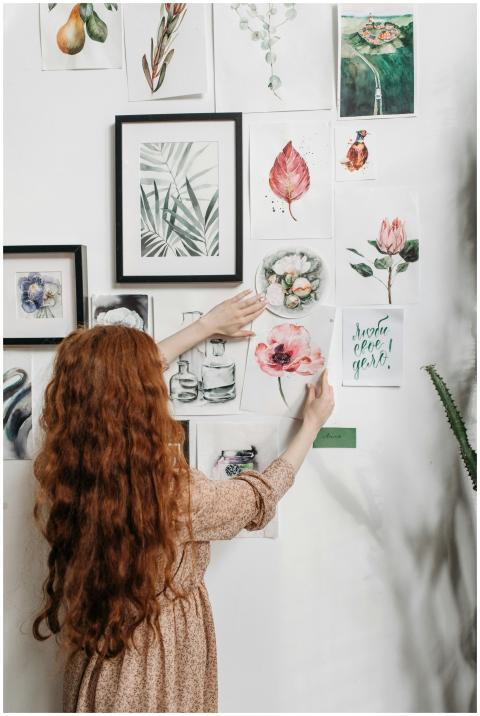 Woman arranging a collection of framed botanical p