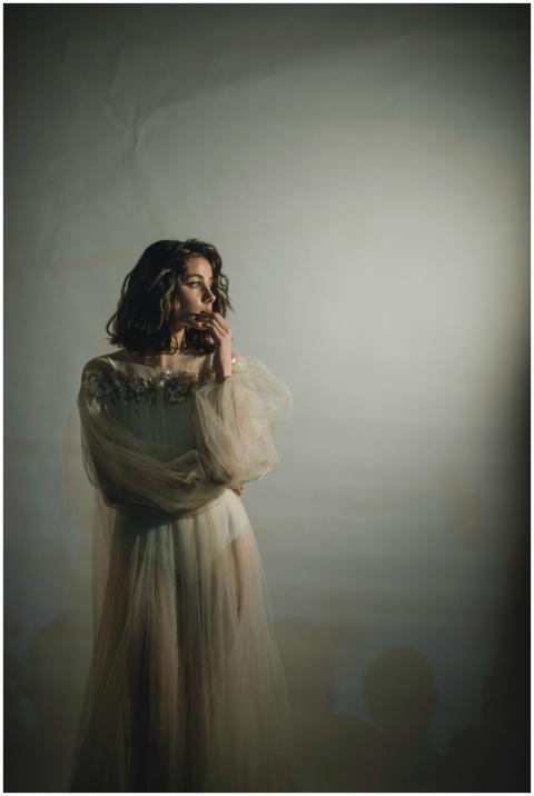 A woman posing gracefully in a flowing, ethereal d