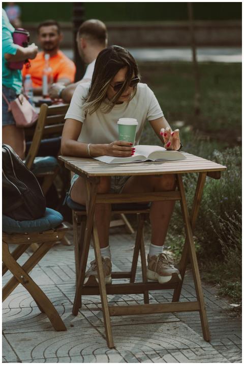 A woman enjoys reading and sipping coffee outdoors