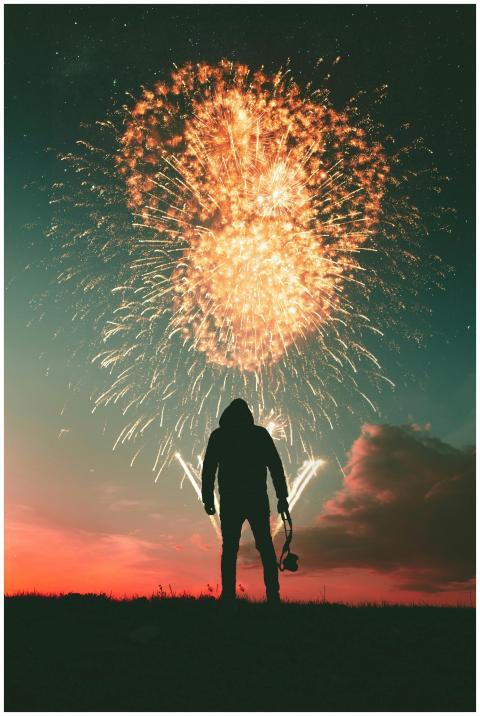 Silhouette of a person with a camera watching a fi