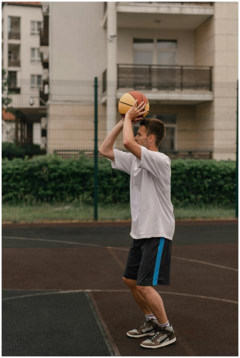 Young caucasian man playing basketball outdoors in
