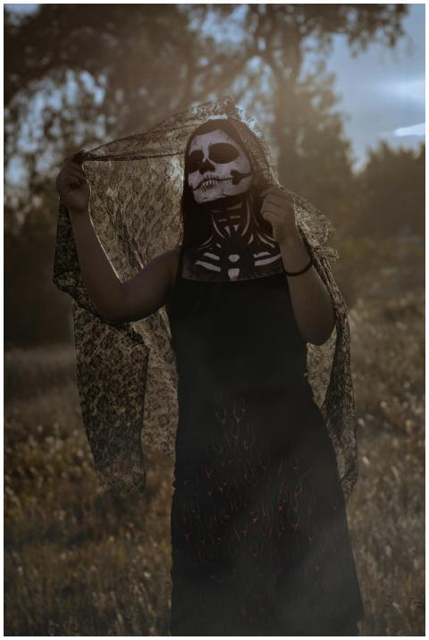 A woman with skull makeup poses in lace outdoors d