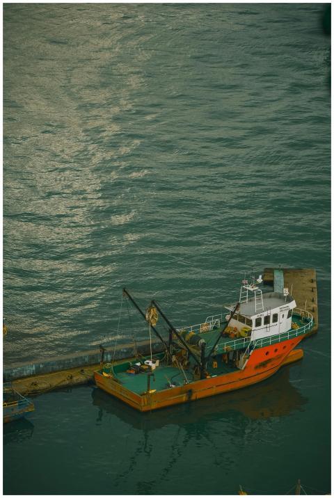 Orange fishing boat docked in Batumi harbor over c