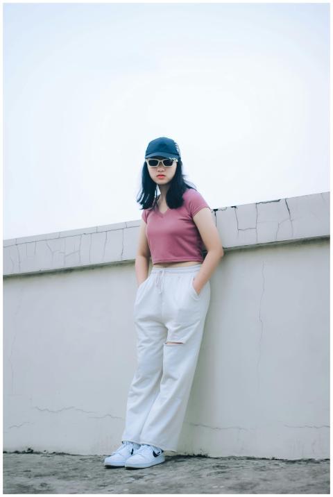 Fashionable woman in pink top and white pants lean