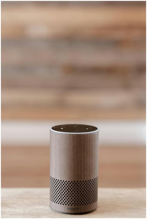 A smart speaker placed on a wooden surface against