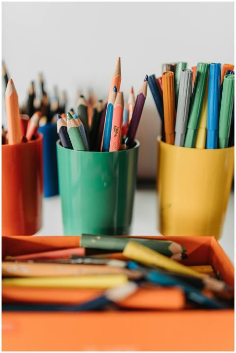Vibrant pencils and pens arranged in colorful cups
