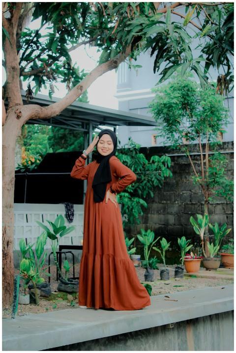 Woman in a long dress posing outdoors under a tree