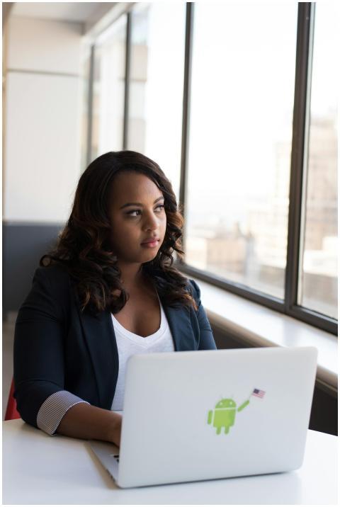 Focused woman using a laptop with Android sticker,