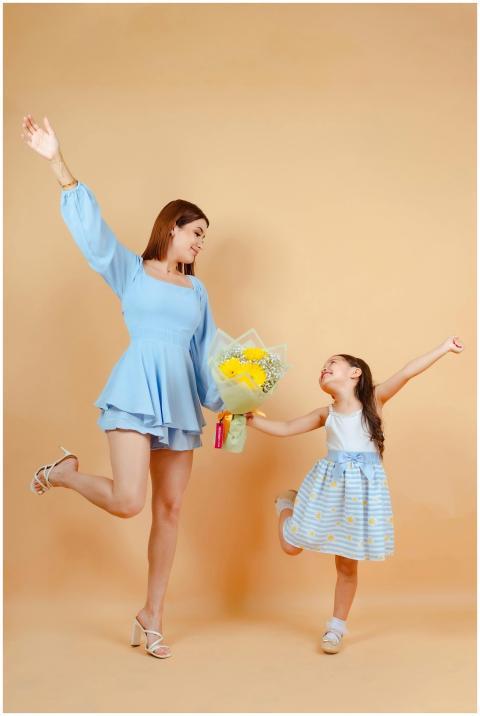 Joyful mother and daughter posing with flowers aga