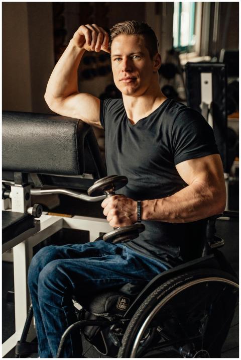 Man in a wheelchair lifts weights, showcasing stre