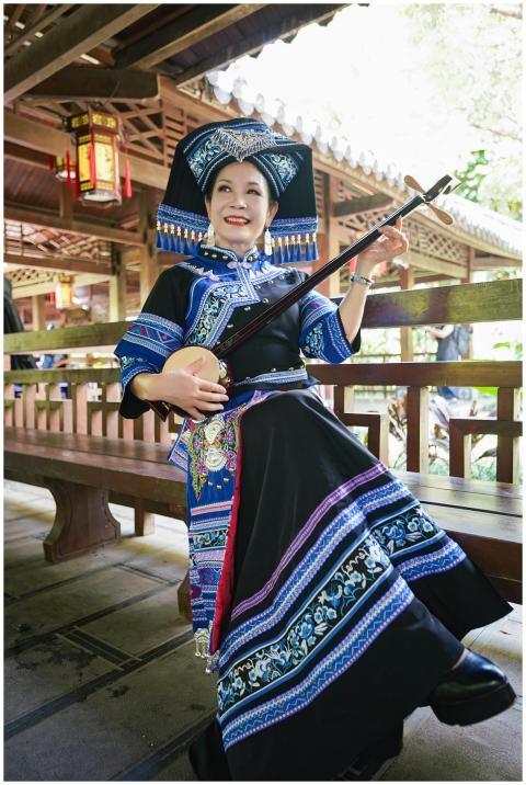 Zhuang woman in traditional attire playing string