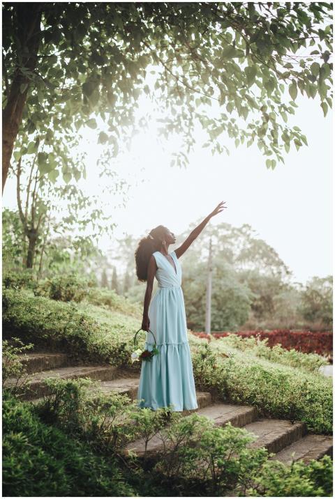 Elegant African woman in a blue dress reaching upw
