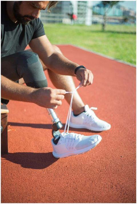 Male athlete with prosthetic leg ties a shoe on a