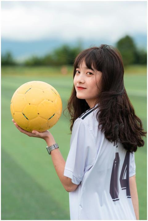 Smiling young woman holding a yellow soccer ball o