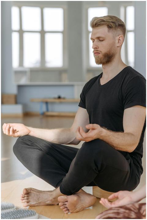 Calm adult man practicing meditation indoors, embr