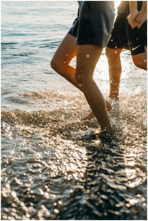 A carefree young couple runs along the beach, spla