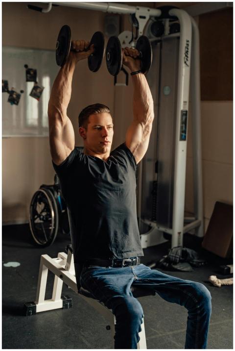Muscular man lifting dumbbells in a gym setting, p