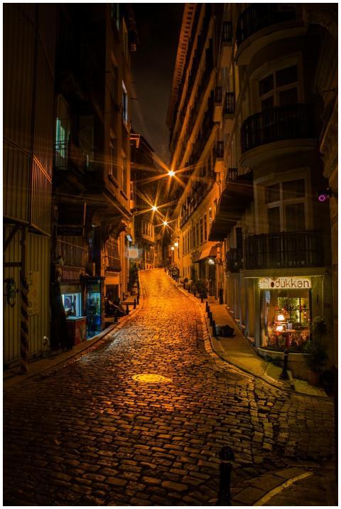 Illuminated cobblestone street in a lively urban a