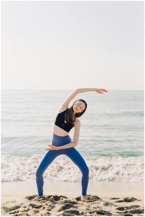 A woman performs yoga in activewear by the beach d