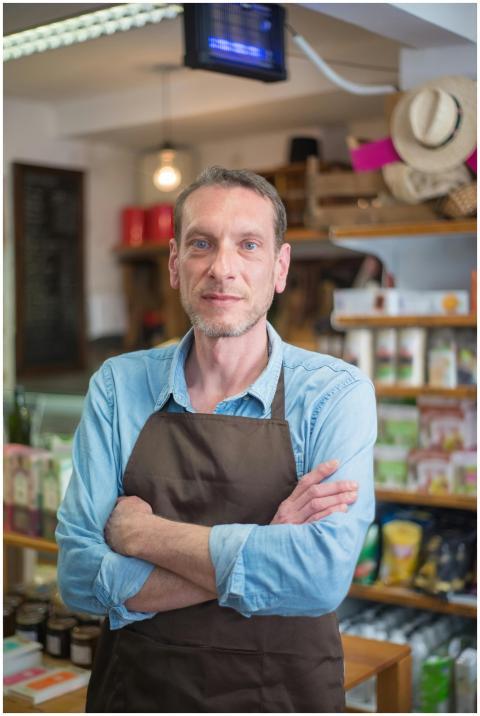 Confident male shop owner with arms crossed in a r
