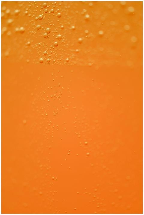 Close-up of bubbles in an orange carbonated drink,