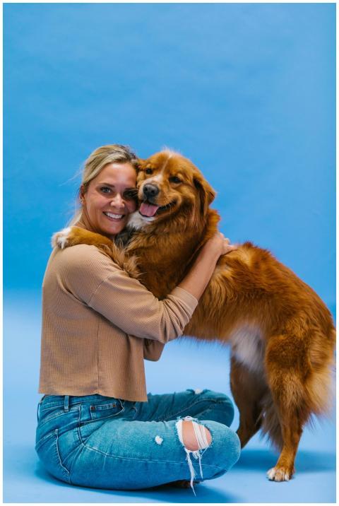A woman joyfully hugs her golden retriever on a vi