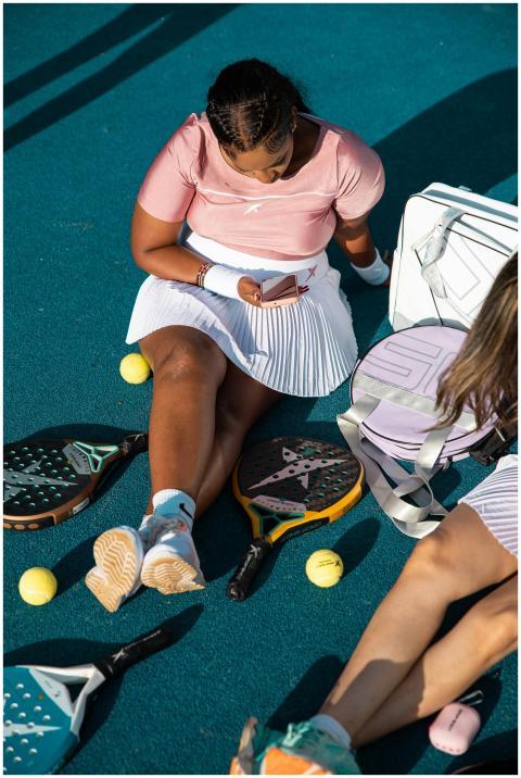 Two women resting on tennis court with paddles and