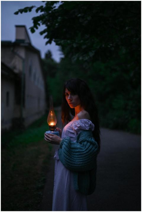 A woman in a sweater holds an illuminated lantern