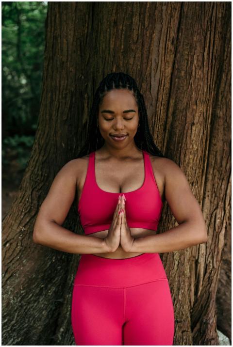 Woman meditating outdoors in pink activewear, eyes