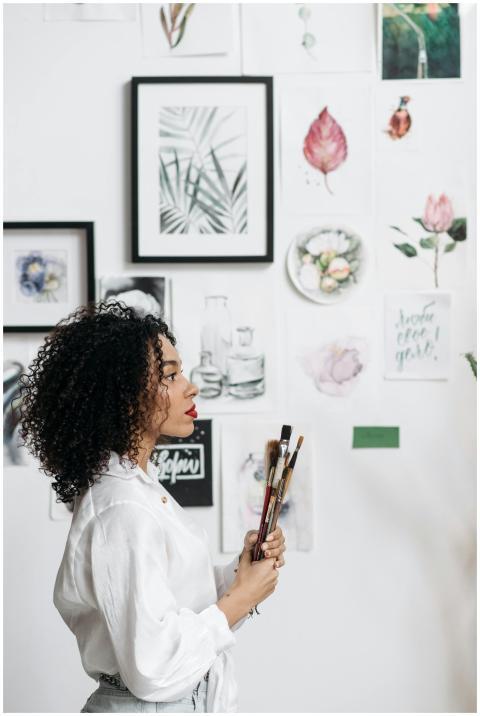 Woman with brushes admiring botanical art on a cre