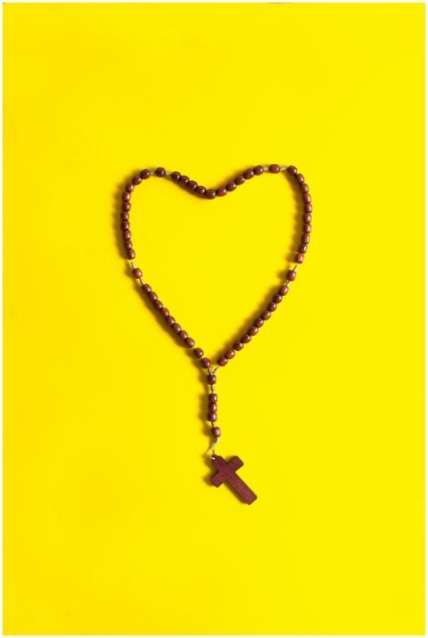 A heart-shaped rosary with a wooden cross placed o