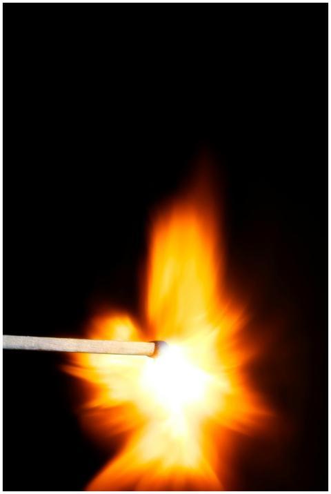 Close-up of a matchstick igniting with a vivid fla