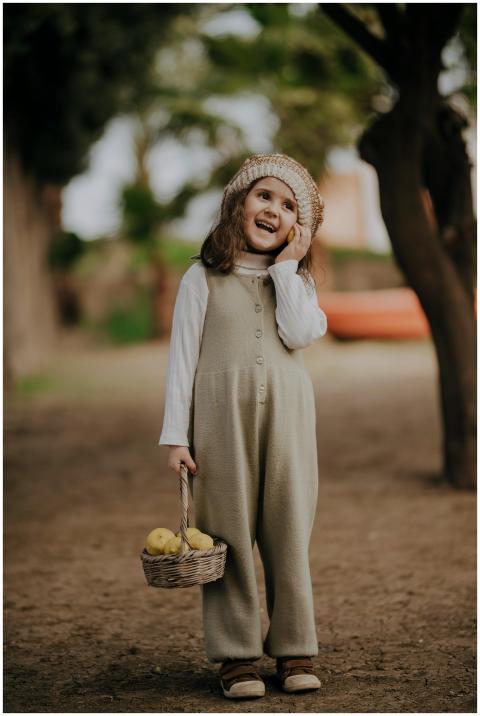 Cheerful child playing outdoors with fruit basket