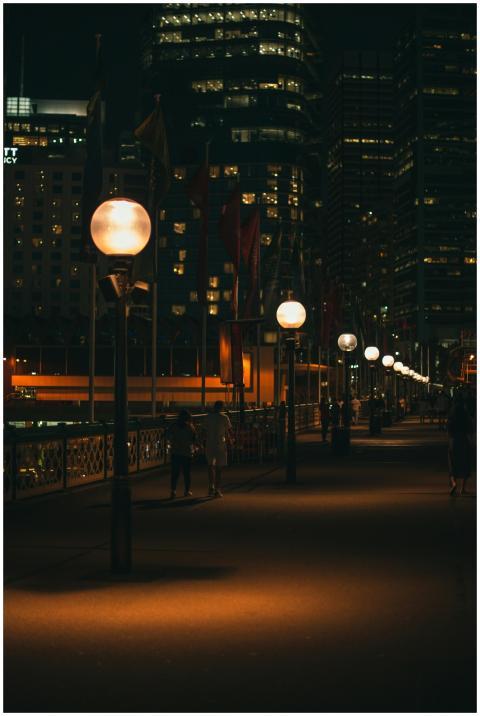 A moody city bridge at night with street lamps lin