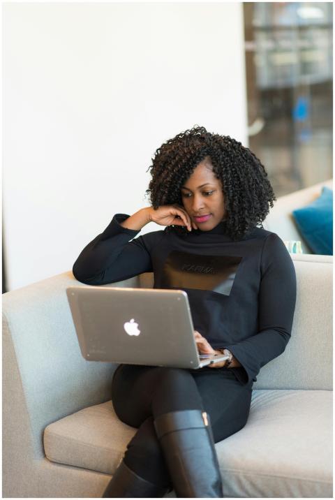 A woman using a laptop while sitting on a sofa in
