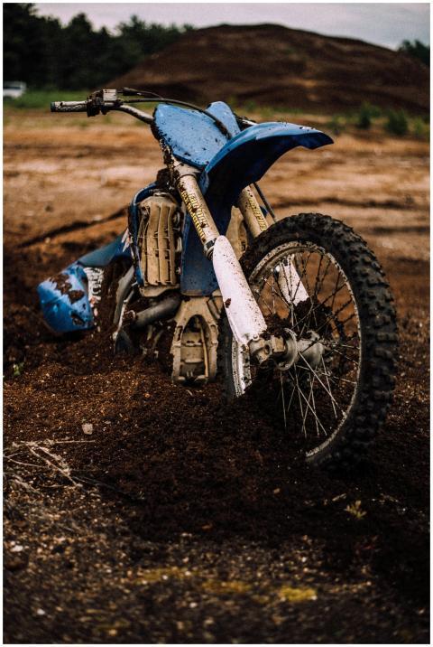 A blue dirt bike stuck in muddy terrain on an outd