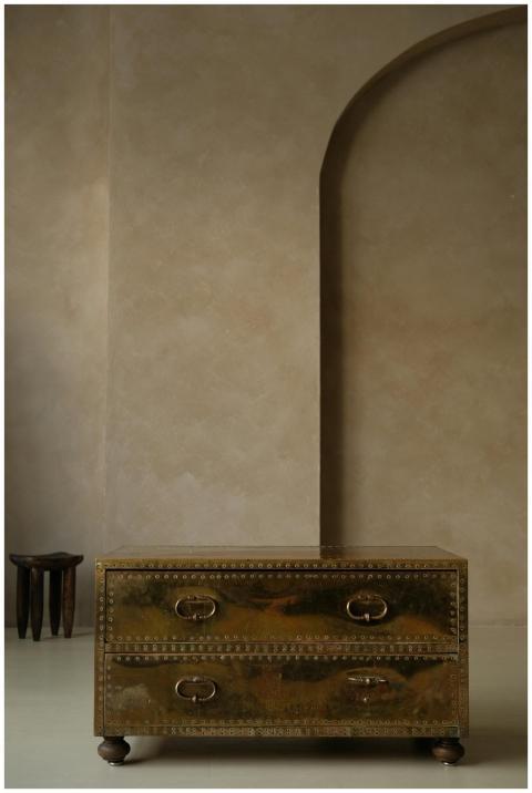 Stylish gold chest in minimalist interior with tex