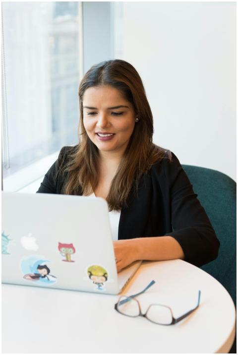 Smiling woman in black blazer working on laptop wi